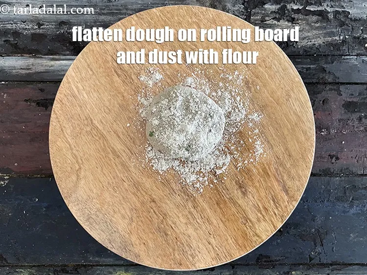Step 16 – <meta charset="UTF-8" />Flatten the dough on a rolling board and dust with bajra flour.&nbsp;&nbsp;<br /> …