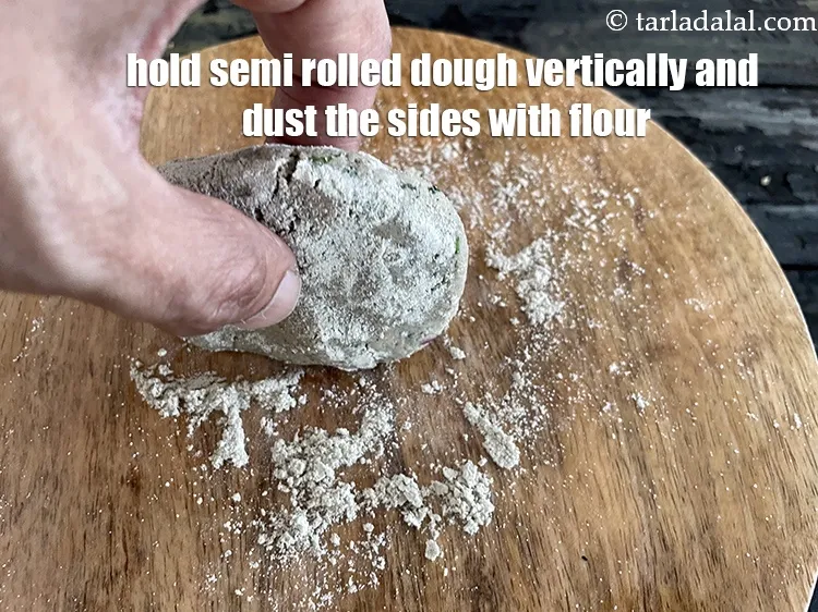 Step 17 – Gently hold the semi rolled roti vertically and dust the edges.