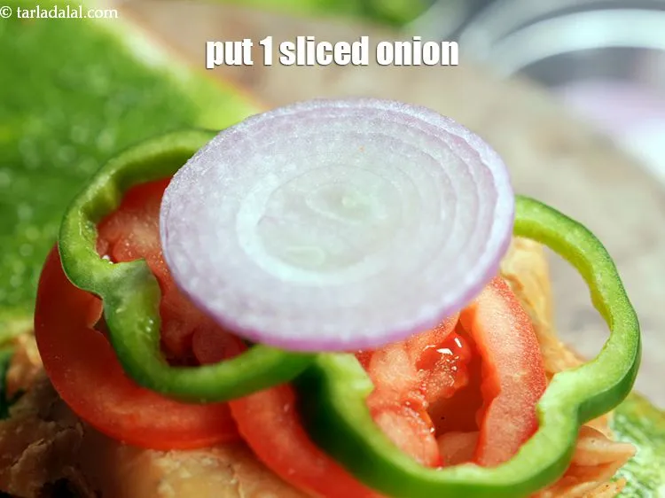 Step 19 – Arrange 1 <a href="https://www.tarladalal.com/glossary-onion-slices-2432i">sliced onions</a>.