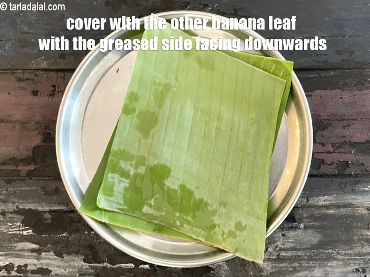 स्टेप 24 – ग्रीज़ किए हुए दूसरे केले के पत्ते से ढ़क दें, …