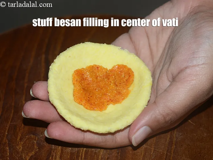 Step 21 – Stuff &frac12; tsp besan filling in the center of the vati.