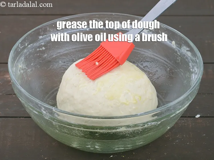 Step 18 – Grease the top of dough with <a href="https://www.tarladalal.com/glossary-olive-oil-451i">olive oil</a> using a brush, to avoid drying.