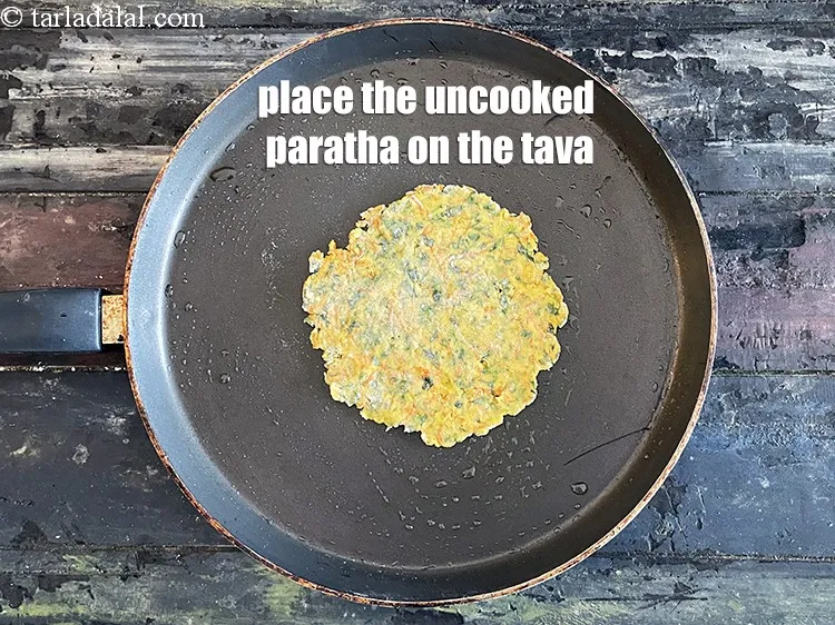 Step 18 – <html><head><meta charset="UTF-8"> </head><body><p>Place the paratha gently on the tava.&nbsp;&nbsp;</p></body></html>