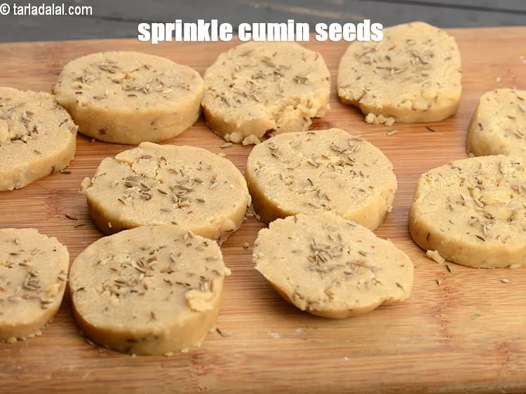 Step 16 – Sprinkle little <a href="https://www.tarladalal.com/glossary-cumin-seeds-jeera-zeera-381i">cumin seeds (jeera)</a> over the cookies.