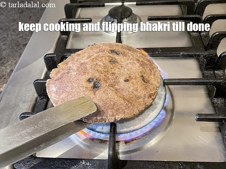 Step 20 – Keep cooking and flipping the bhakri on both side with a chimta.&nbsp;