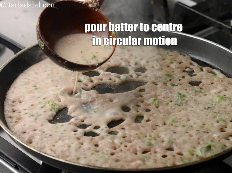 Step 19 – Once the tava is greased properly, pour the batter using a ladle from the edges …