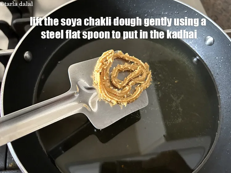 Step 29 – Lift the soya chakli&nbsp;dough gently using the steel flat spoon tp put in a kadhai.