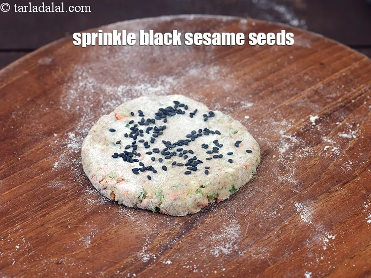 Step 19 – Sprinkle 1/4 tsp&nbsp;<a href="https://www.tarladalal.com/glossary-black-sesame-seeds-kala-til-kale-til-862i">black sesame seeds (kala til)</a>&nbsp;for rolling evenly over it.