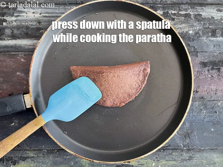 Step 24 – Press down with a spatula on the paratha while cooking.