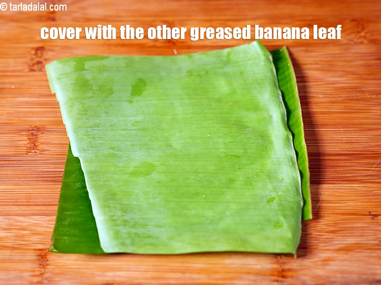 Step 22 – <meta charset="UTF-8" />Cover with the other greased banana leaf with the greased side facing downwards.&nbsp;&nbsp;