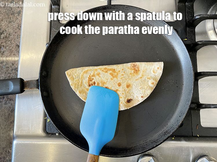 Step 38 – Use a spatula and press down to cook the stuffed paratha evenly.