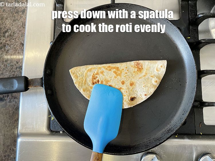Step 43 – Use a <strong>spatula and press down</strong> to cook the <strong>stuffed gobi methi paratha </strong>&nbsp;evenly.