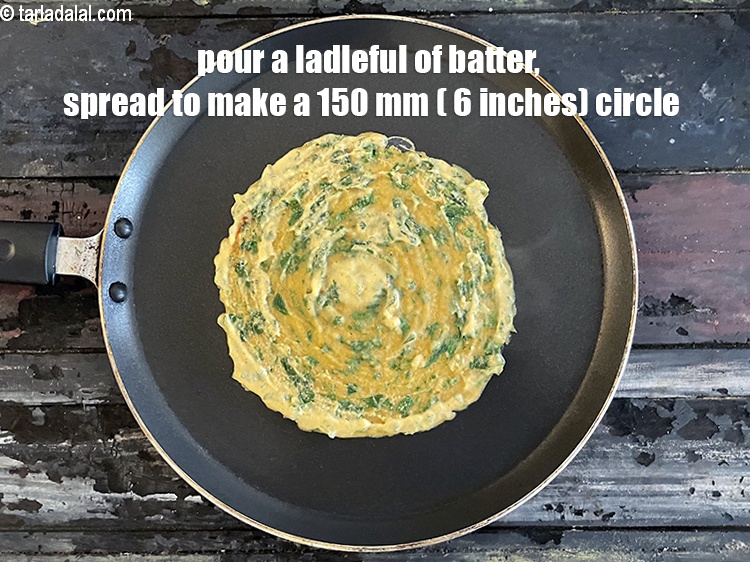 Step 19 – <meta charset="UTF-8" /> Pour a ladleful of the batter on the tava (griddle) and spread …