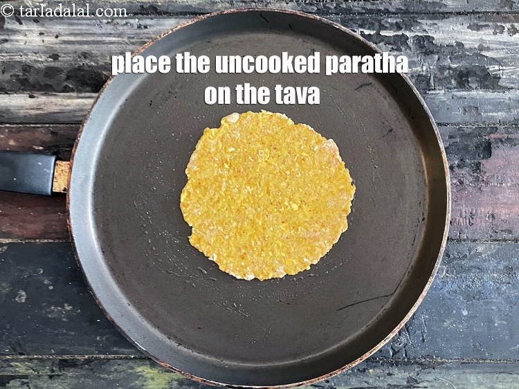 Step 21 – <meta charset="UTF-8" />Place the paratha gently on the tava.&nbsp;&nbsp;