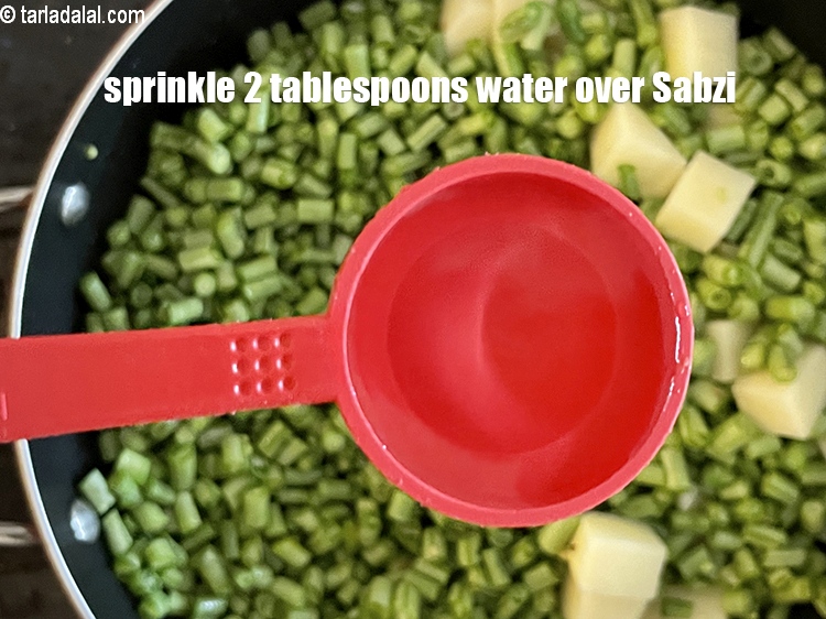 स्टेप 20 – सब्जी के ऊपर 2 बड़े चम्मच पानी छिड़कें।