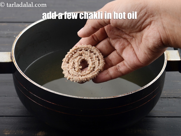 Step 21 – Heat the <a href="https://www.tarladalal.com/glossary-oil-671i">oil</a>&nbsp;for deep-frying in a kadhai and&nbsp;add a few chakli&nbsp;at a time&nbsp;in it.