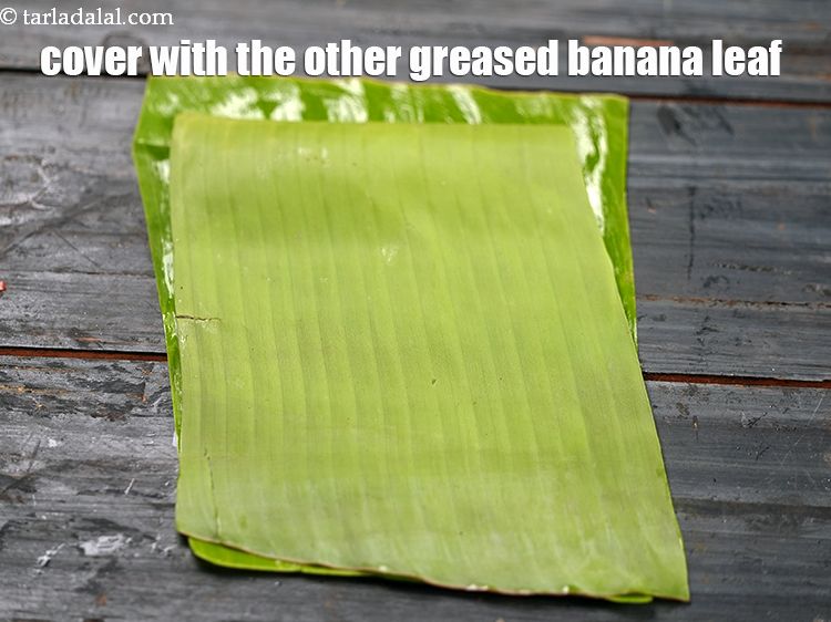 Step 24 – <meta charset="UTF-8" />Cover with the other greased banana leaf with the greased side facing downwards.&nbsp;