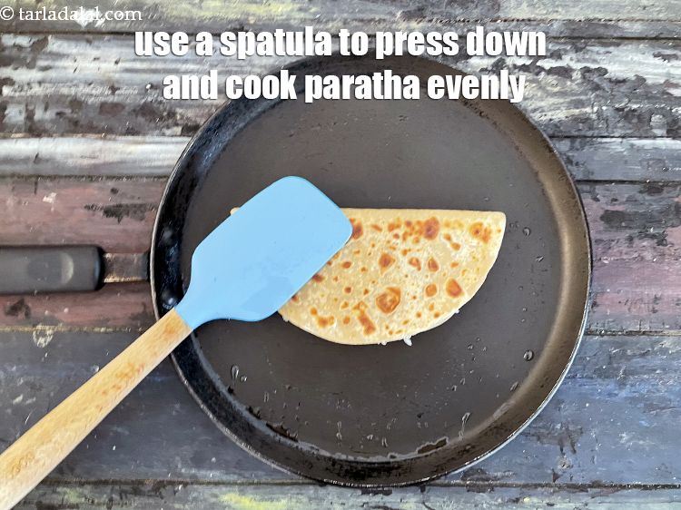 Step 48 – <meta charset="UTF-8" /> Use a&nbsp;<strong>spatula and press down</strong>&nbsp;to cook the<strong>&nbsp;mooli dhania paratha&nbsp;</strong>&nbsp;evenly.