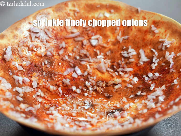 Step 22 – Sprinkle &frac14; cup finely <a href="https://www.tarladalal.com/glossary-chopped-onions-722i">chopped onions</a> evenly over it.