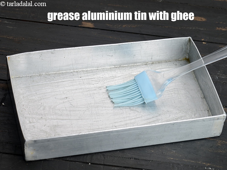 Step 5 – To make <strong>rajgira chikki</strong>, grease the aluminium tin with little ghee and keep aside.