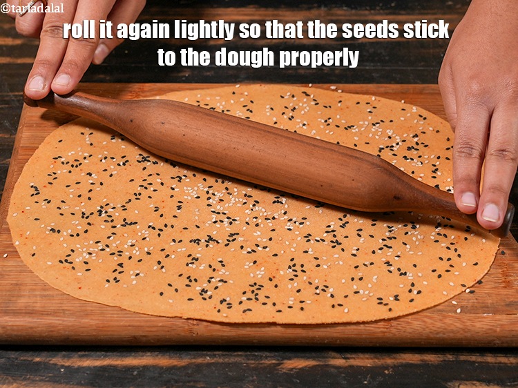 Step 23 – <p>Roll it again lightly so that the seeds stick to the dough properly.</p>