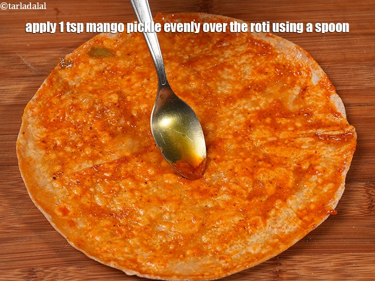 Step 25 – Apply 1 tsp <a href="https://www.tarladalal.com/mango-pickle-30931r">mango pickle</a> evenly over the roti using a spoon.