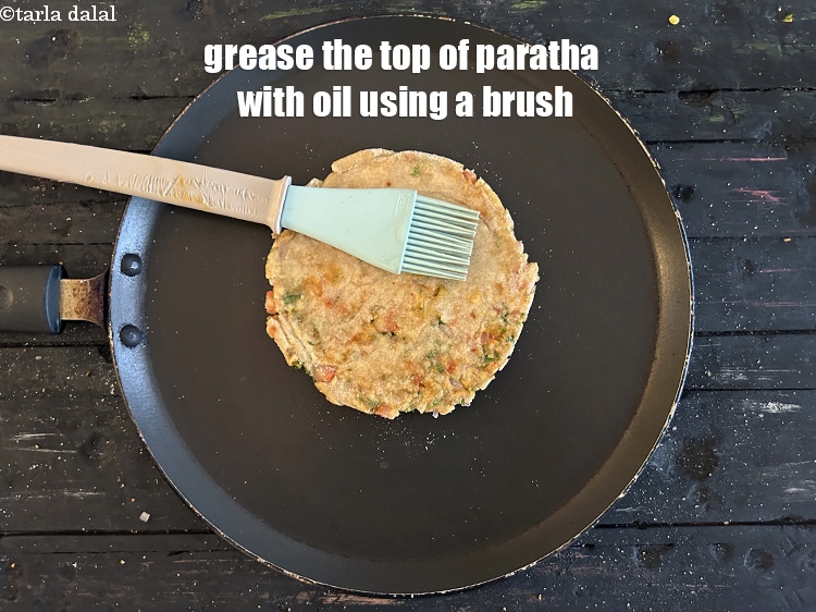 स्टेप 30 – परांठे के ऊपरी हिस्से को ब्रश की सहायता से तेल …