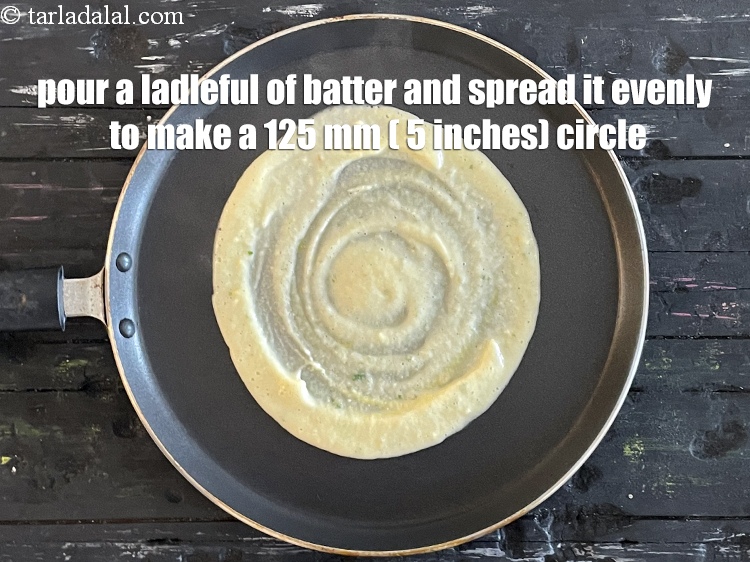 Step 32 – Pour a ladleful of the batter on the tava and spread it evenly to make …