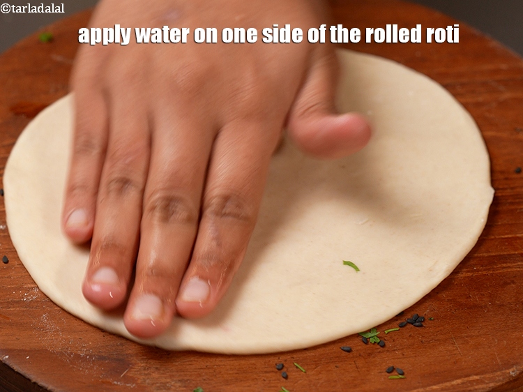 स्टेप 24 – बेली हुई रोटी के एक तरफ पानी लगायें।