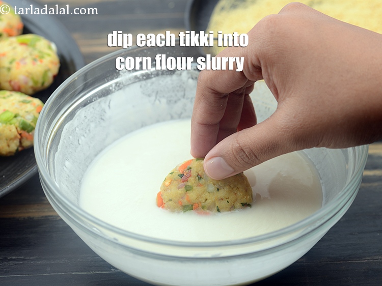 स्टेप 24 – हर टिक्की को कॉर्नफ्लोर के घोल में डुबोएँ।