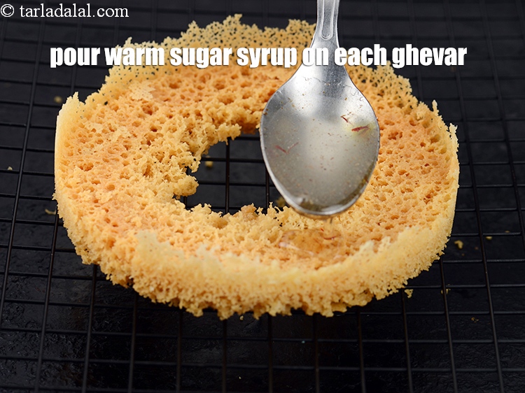 स्टेप 27 – प्रत्येक घेवर पर गरम चीनी की चाशनी डालें, चाशनी को …