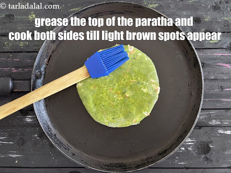 स्टेप 25 – पराठे के ऊपर थोड़ा सा तेल लगाकर चिकना कर लें, …