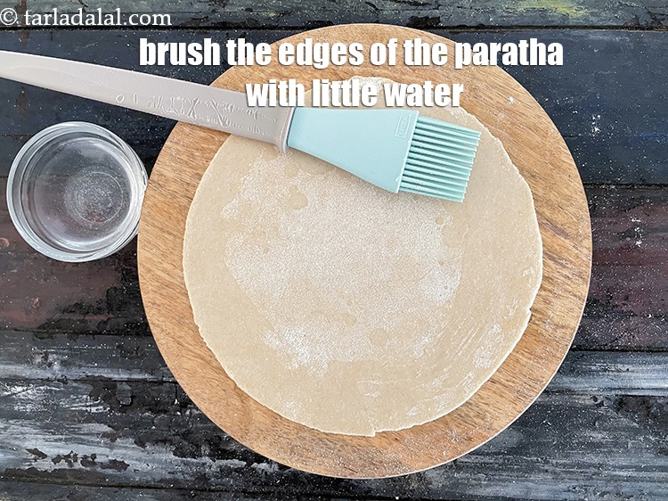 Step 27 – Brush the edges of the rolled paratha with a little water.