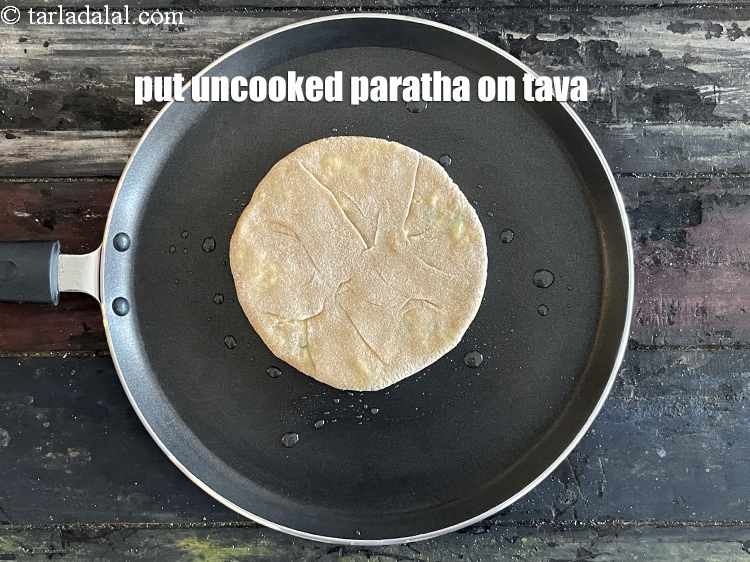स्टेप 25 – कच्चे पराठे को तवे पर डालें।&nbsp;