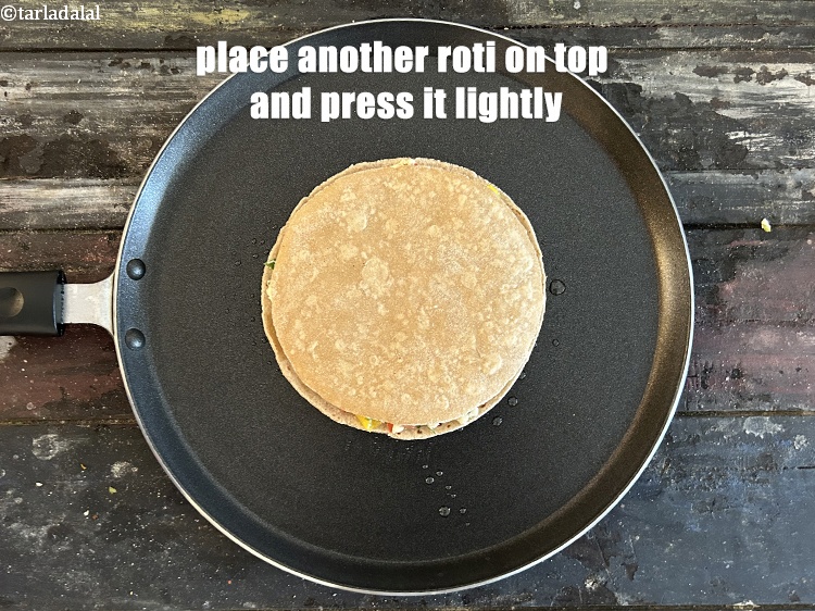 स्टेप 26 – इसके ऊपर दूसरी रोटी रखें और हल्का सा दबा दें।