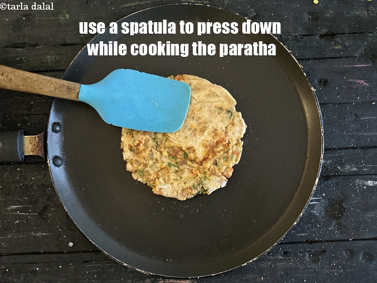 स्टेप 39 – पराठा पकाते समय नीचे दबाने के लिए स्पैटुला का प्रयोग …