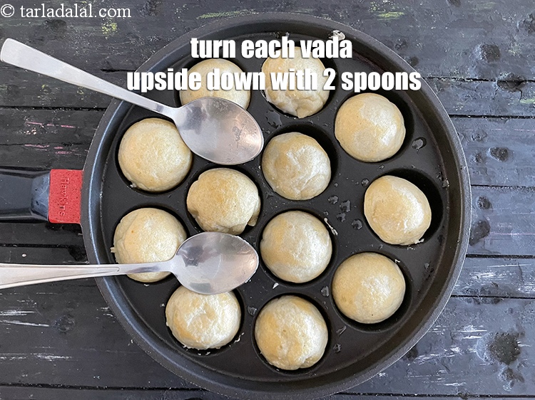 Step 26 – <meta charset="UTF-8" />Turn each vada upside down using a fork or 2 spoons.&nbsp;