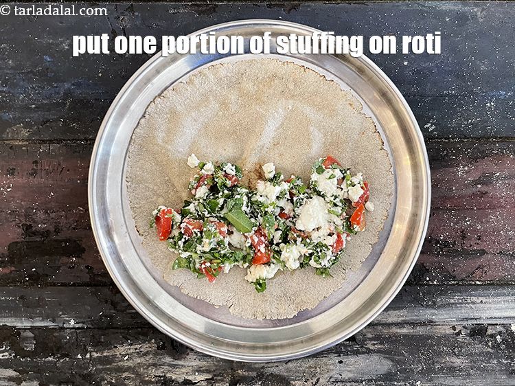 Step 29 – In a semi cooked bajra roti, put one portion of paneer stuffing on it. Place …