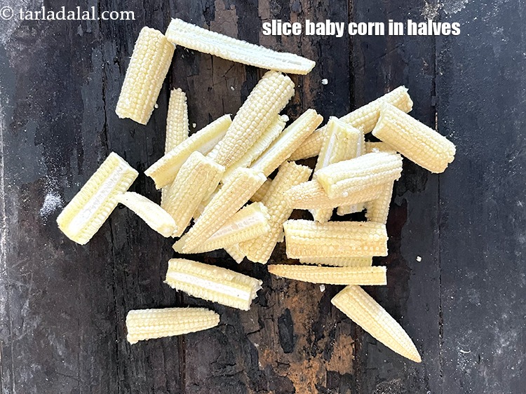 स्टेप 27 – बेबी कॉर्न को आधे टुकड़ो में काट लें।