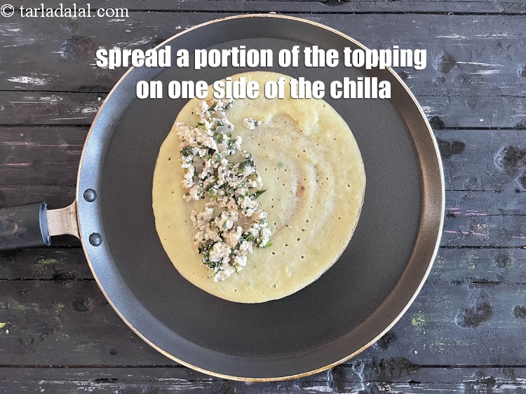 Step 35 – <meta charset="UTF-8" /> Spread 1/4th&nbsp;of the paneer topping on one side of the chilla.