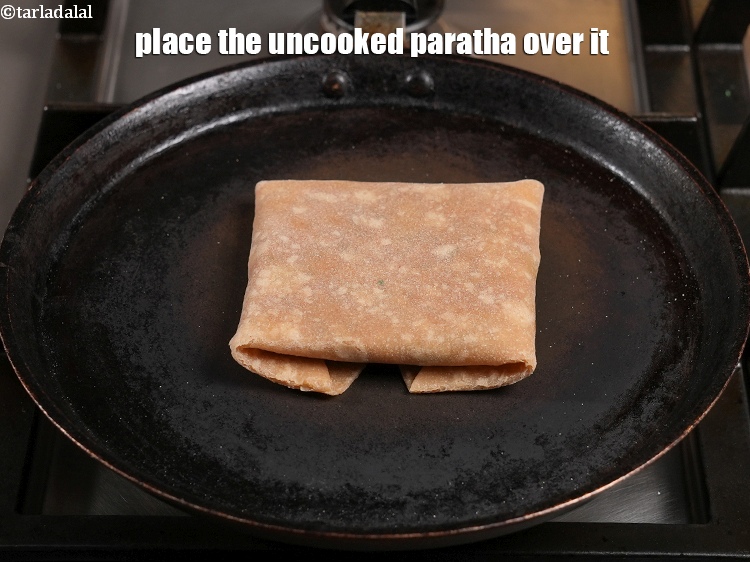 Step 58 – <meta charset="UTF-8" /> Place the uncooked&nbsp;<strong>rajma cheese paratha&nbsp;</strong>over it.&nbsp;<u><em>The flat surface of the paratha should …