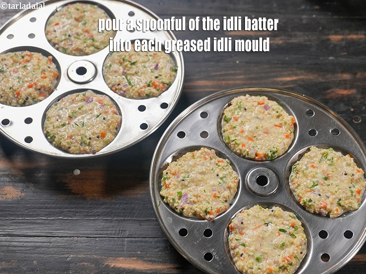 स्टेप 28 – प्रत्येक चिकने इडली सांचे में एक चम्मच इडली बैटर डालें।