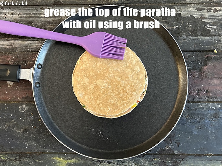 स्टेप 30 – परांठे के ऊपरी हिस्से को ब्रश की सहायता से तेल …