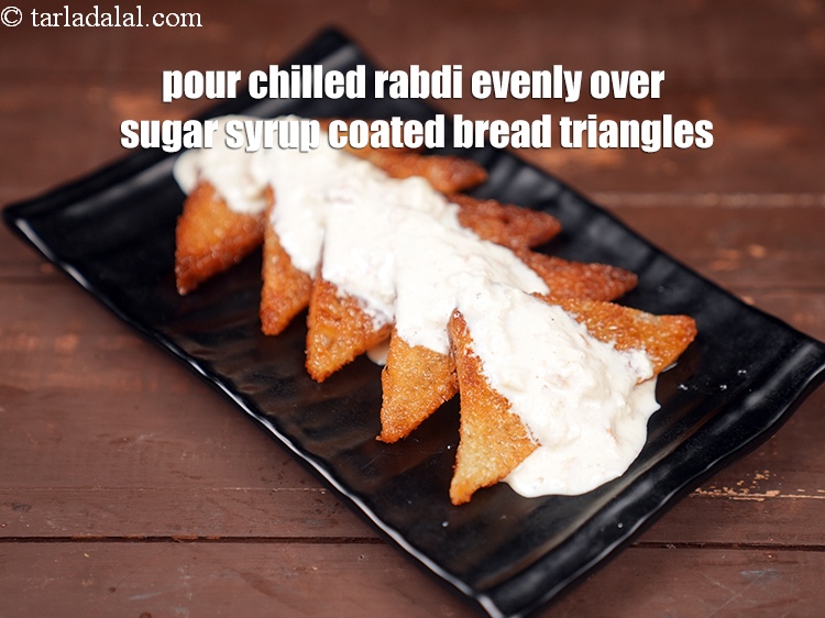 Step 29 – Pour the chilled rabdi evenly over the sugar syrup coated bread triangles.