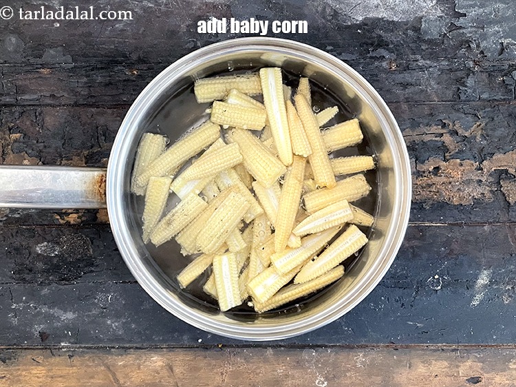 स्टेप 29 – आधे कटे हुए बेबी कॉर्न डालें।