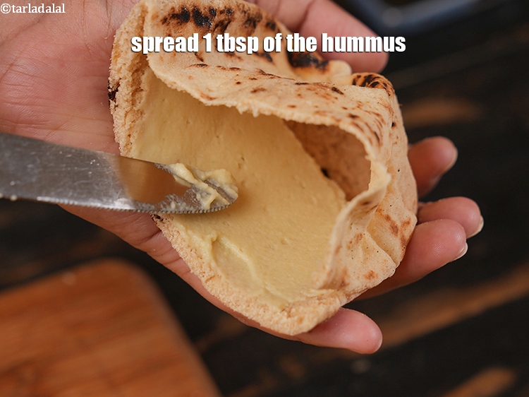 Step 31 – Take a pita bread halve.&nbsp;Spread 1 tbsp of the hummus