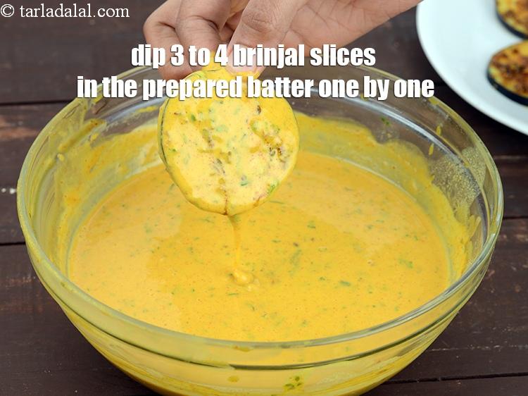 Step 31 – Dip 3 to 4 brinjal slices in the prepared batter one by one.&nbsp;