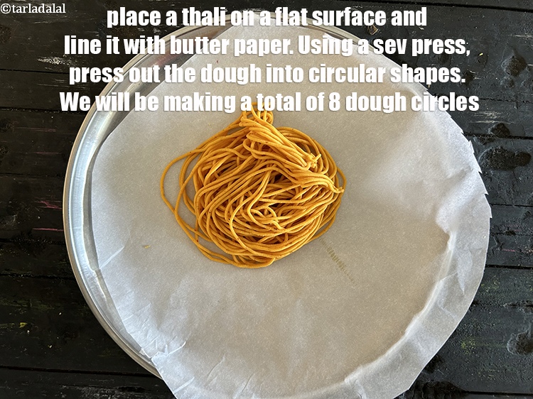 Step 43 – Place a thali on a flat surface and line it with butter paper. This will …