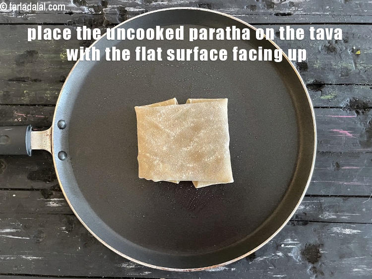 Step 49 – <meta charset="UTF-8" /> Place the uncooked&nbsp;<strong>rajma cheese paratha&nbsp;</strong>over it.&nbsp;<u><em>The flat surface of the paratha should …