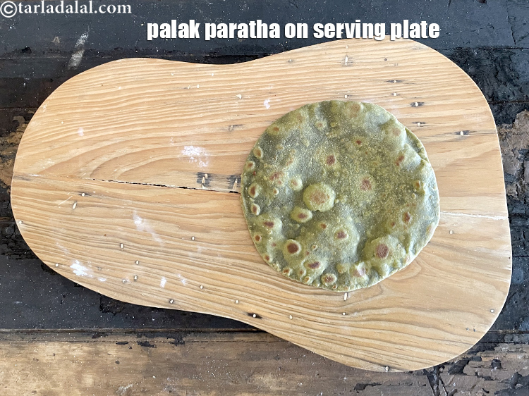 स्टेप 57 – पके हुए पालक के पराठे को सर्विंग प्लेट पर रखें।